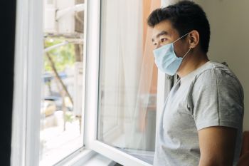 Side-view-man-with-medical-mask-home-during-pandemic-looking-through-window.jpg